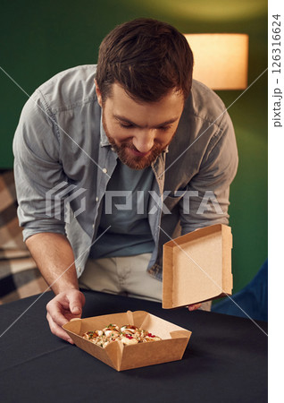 Man in casual clothes is with sushi that is in the paper eco box Man in casual clothes is with sushi that is in the paper eco box 126316624