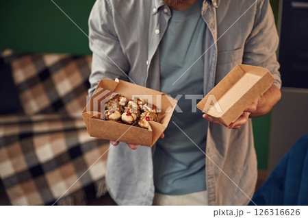 Opening the paper eco box. Man in casual clothes is holding sushi Opening the paper eco box. Man in casual clothes is holding sushi 126316626