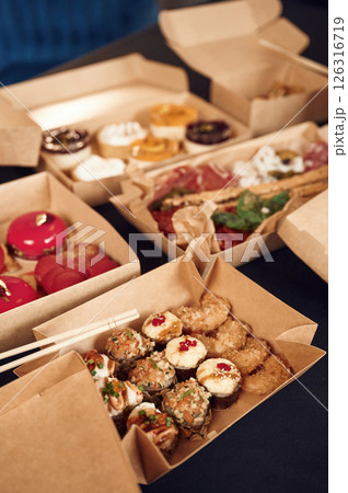 Close up view of table with food on it. Meat, vegetables, sushi, French fries, burger, mushrooms Close up view of table with food on it. Meat, vegetables, sushi, French fries, burger, mushrooms 126316719