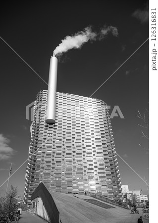 Amager Bakke stands tall in Copenhagen, blending sustainability and recreation. The striking architecture features a smoking chimney, showcasing its role in energy production and community space. Amager Bakke stands tall in Copenhagen, blending sustainability and recreation. The striking architecture features a smoking chimney, showcasing its role in energy production and community space. 126316831