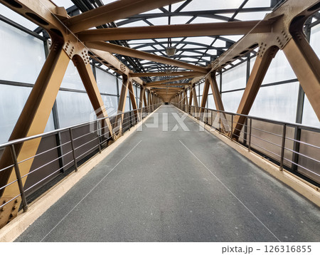 Modern pedestrian bridge spans over urban landscape in the heart of the city during a cloudy day 126316855
