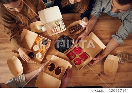 Top view of table with food on it, hands of the people taking it, eating. Macarons, blueberries, desserts, pastry meal 126317144