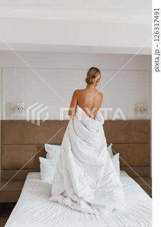 Seductive young bride posing on the bed in hotel room wrapped in white blanket 126317491