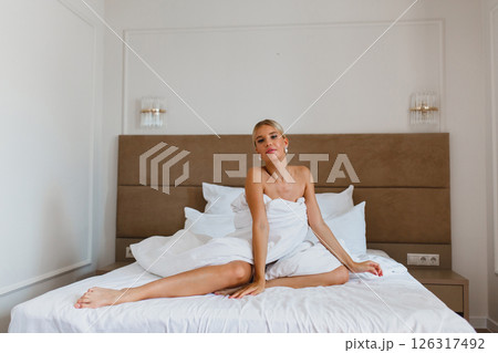 Seductive young bride posing on the bed in hotel room wrapped in white blanket 126317492