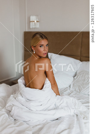 Close-up portrait of seductive young bride in hotel room wrapped in white blanket Close-up portrait of seductive young bride in hotel room wrapped in white blanket 126317605