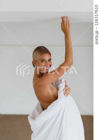 Close-up portrait of seductive young bride in hotel room wrapped in white blanket 126317610