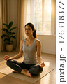朝日の差し込む部屋で瞑想する女性 126318372