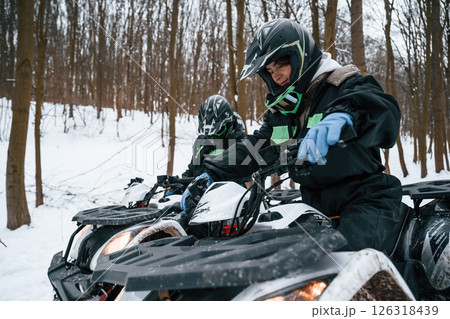 Woman with her friend. Two people are riding ATV in the winter forest 126318439