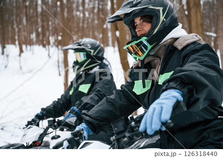 Woman with her friend. Two people are riding ATV in the winter forest Woman with her friend. Two people are riding ATV in the winter forest 126318440
