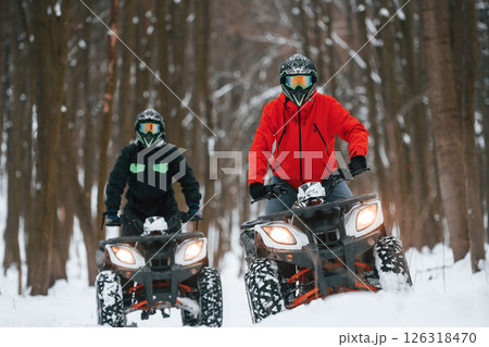 Front view. Two people are riding ATV in the winter forest 126318470