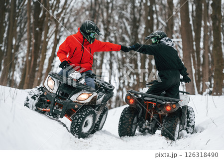 Knocking the fists. Two people are riding ATV in the winter forest Knocking the fists. Two people are riding ATV in the winter forest 126318490