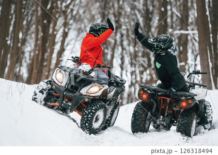 Making high five. Two people are riding ATV in the winter forest 126318494