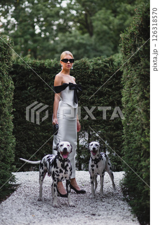 Young beautiful bride in stylish elegant dress posing in park with two dalmatians Young beautiful bride in stylish elegant dress posing in park with two dalmatians 126318570