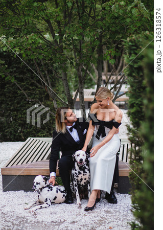 Stylish young beautiful newlywed couple walking at wedding in park with two dalmatians 126318574