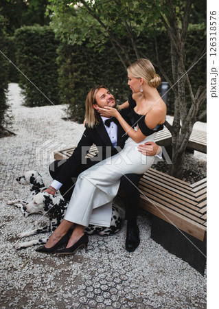 Stylish young beautiful newlywed couple walking at wedding in park with two dalmatians 126318576
