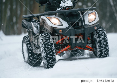 Snow, trees, adventure. Man is riding ATV outdoors in the winter forest 126318618