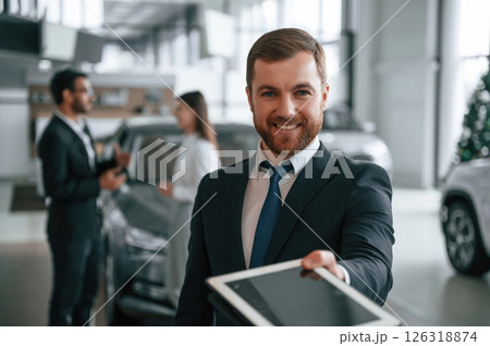 Using graphic tablet. Three people are working together in the car showroom Using graphic tablet. Three people are working together in the car showroom 126318874