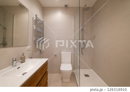 Modern bathroom with glass shower partition, white toilet, large mirror and wood vanity unit Modern bathroom with glass shower partition, white toilet, large mirror and wood vanity unit 126318910