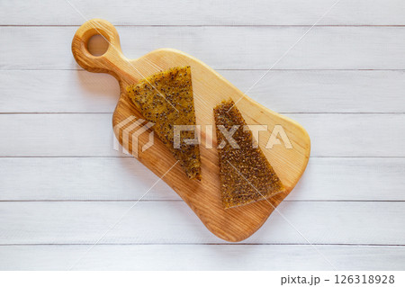 Top view of two yellow fruit pastille slices with visible seeds placed on light wood board over white wooden table Top view of two yellow fruit pastille slices with visible seeds placed on light wood board over white wooden table 126318928