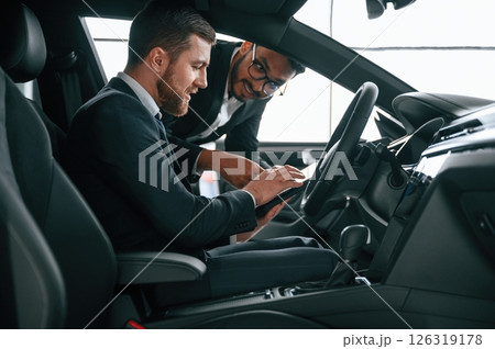 Side view. Man showing automobile interior to the customer Side view. Man showing automobile interior to the customer 126319178