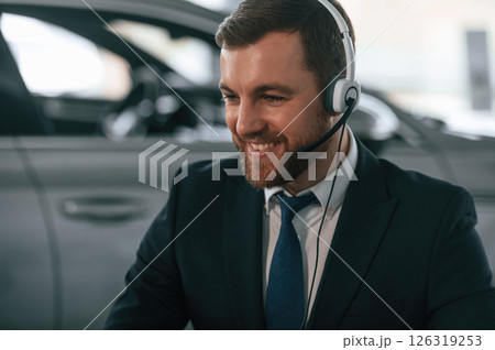 Man is sitting and working in the car showroom Man is sitting and working in the car showroom 126319253