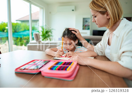Mother helps daughter with drawing in bright living room 126319328