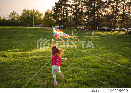 Children joyfully flying colorful kites in a sunny park Children joyfully flying colorful kites in a sunny park 126319400