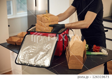 Man packs paper eco boxes into a bag for food delivery 126319673