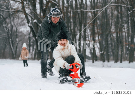 Sled ride. Mother and father is with daughter have walk outdoors at the winter season 126320102