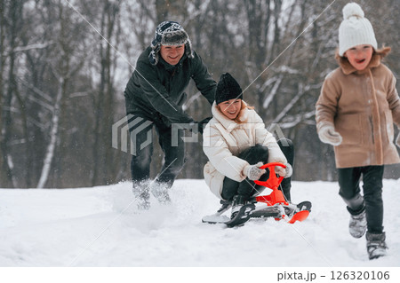 Sled ride. Mother and father is with daughter have walk outdoors at the winter season Sled ride. Mother and father is with daughter have walk outdoors at the winter season 126320106