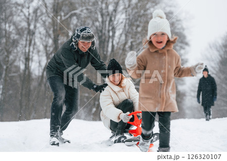 Woman is on sled ride. Happy family is outdoors, enjoying snow time at winter together Woman is on sled ride. Happy family is outdoors, enjoying snow time at winter together 126320107