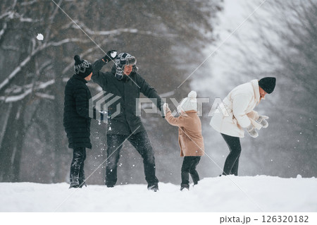 Playing snowballs. Happy family is outdoors, enjoying snow time at winter together Playing snowballs. Happy family is outdoors, enjoying snow time at winter together 126320182