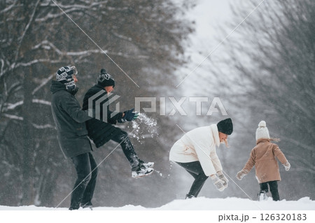 Playing snowballs. Happy family is outdoors, enjoying snow time at winter together Playing snowballs. Happy family is outdoors, enjoying snow time at winter together 126320183