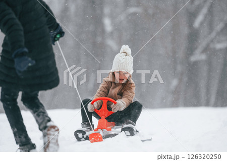 Brother with his sister is outdoors at winter season. Taking girl to a sled Brother with his sister is outdoors at winter season. Taking girl to a sled 126320250