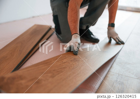 Close up view. Man is installing new laminated wooden floor Close up view. Man is installing new laminated wooden floor 126320415