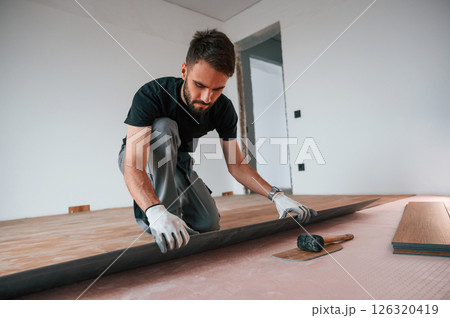 Hand work. Man is installing new laminated wooden floor Hand work. Man is installing new laminated wooden floor 126320419