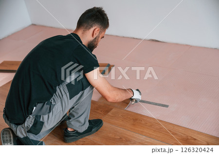 Using the rubber hammer. Man is installing new laminated wooden floor Using the rubber hammer. Man is installing new laminated wooden floor 126320424