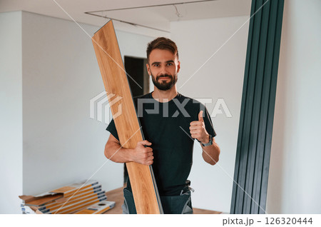 Holding the planks. Man is installing new laminated wooden floor Holding the planks. Man is installing new laminated wooden floor 126320444