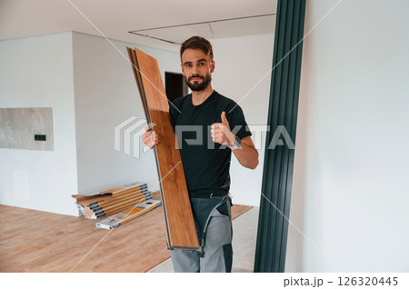 Holding the planks. Man is installing new laminated wooden floor Holding the planks. Man is installing new laminated wooden floor 126320445