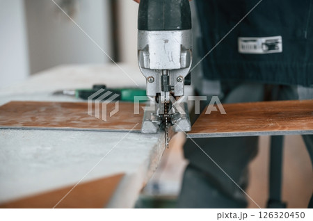 Cutting the planks. Man is installing new laminated wooden floor 126320450