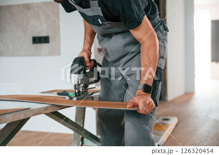 Cutting the planks. Man is installing new laminated wooden floor Cutting the planks. Man is installing new laminated wooden floor 126320454