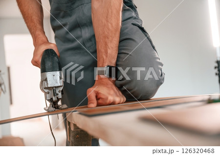 Using jigsaw to cut pieces. Man is installing new laminate wooden floor 126320468