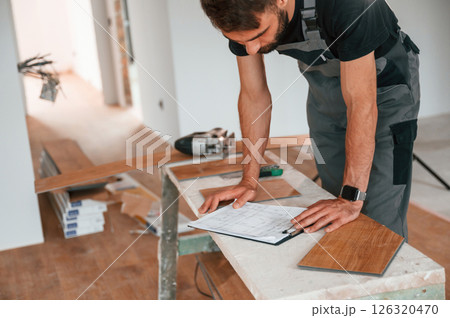 Reading the information. Man is installing new laminated wooden floor Reading the information. Man is installing new laminated wooden floor 126320470