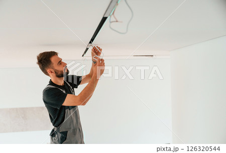 Installing lighting equipment on the ceiling. Man is working indoors at domestic room Installing lighting equipment on the ceiling. Man is working indoors at domestic room 126320544