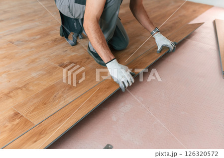 Hand work. Man is installing new laminated wooden floor 126320572