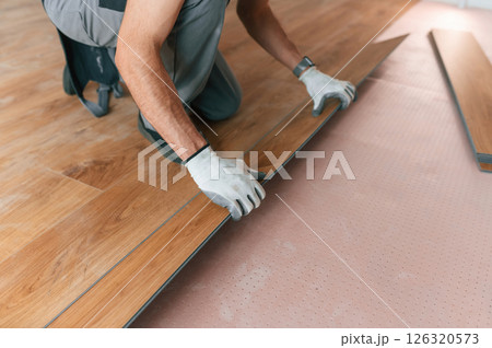 Man is installing new laminated wooden floor 126320573