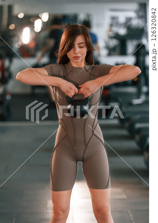 Lifting dumbbell. Beautiful woman with sport body type is in the gym 126320842