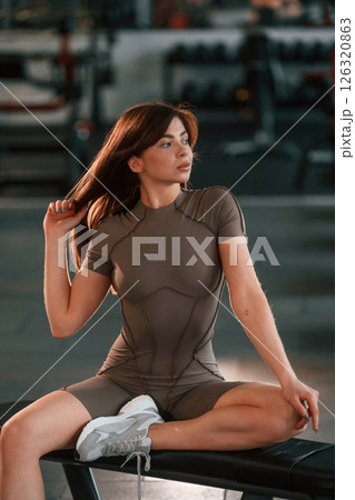 In fitness clothes, sitting and resting. Beautiful woman with sport body type is in the gym 126320863