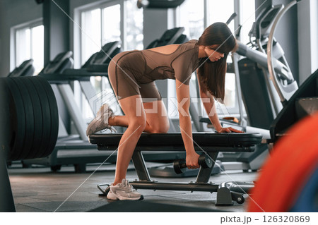 Hands exercises. Lifting dumbbell. Beautiful woman with sport body type is in the gym Hands exercises. Lifting dumbbell. Beautiful woman with sport body type is in the gym 126320869