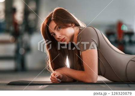 Lying down on the yoga mat and resting. Beautiful woman with sport body type is in the gym 126320879